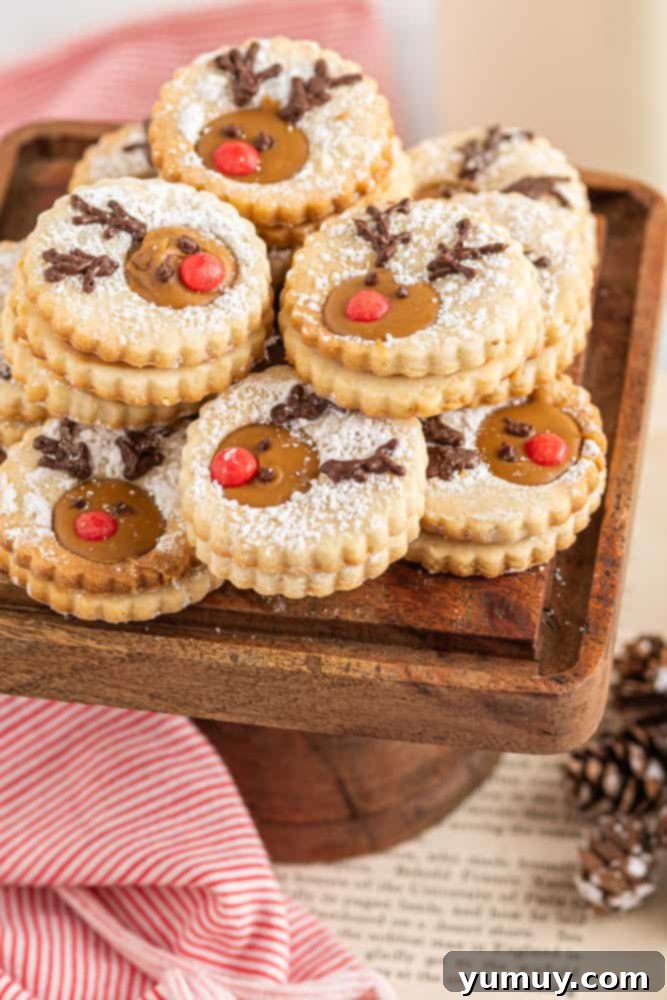 A beautifully arranged stack of reindeer linzer cookies on a rustic wooden serving tray, showcasing their detailed decoration.