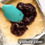 Luscious Raspberry Bars 7 Spreading raspberry jam over the bottom crust in a baking pan.