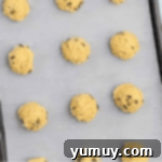 chocolate chip cookie dough balls on a baking sheet.