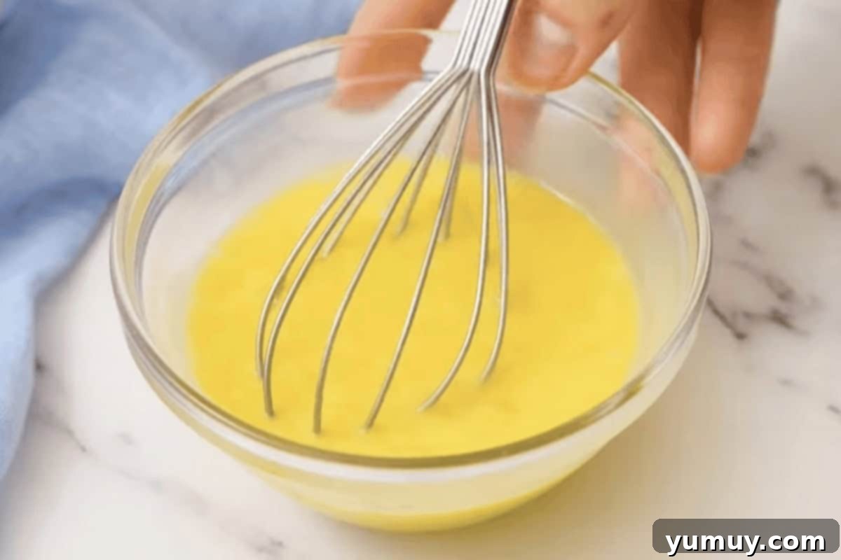 whisking raw eggs in a glass bowl.