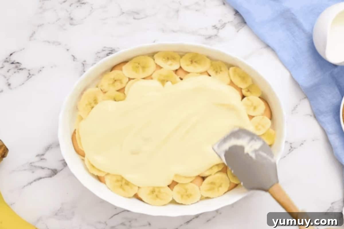 spreading pudding over banana slices in a baking dish.