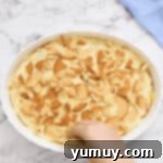 crumbling vanilla wafers over banana pudding in a baking dish.