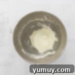 Creamy marshmallow creme filling being gently mixed in a metal bowl, looking incredibly fluffy and inviting.