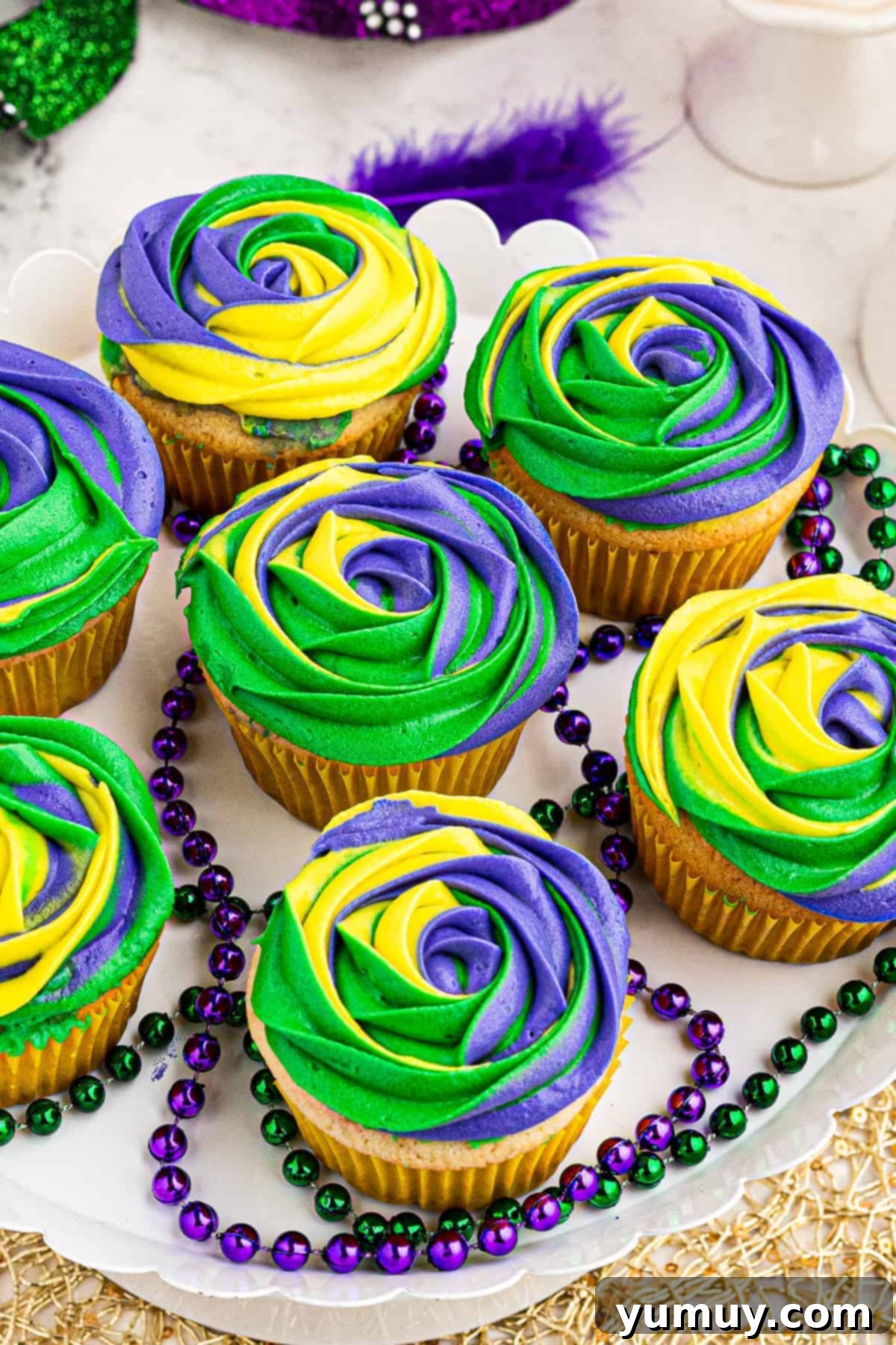 Vibrant purple, yellow, and green King Cake Mardi Gras cupcakes on a platter, ready for celebration.