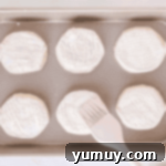 Unbaked biscuits arranged on a baking sheet, coated with heavy cream and granulated sugar.