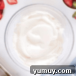 Smooth, thick homemade whipped cream with yogurt in a clear glass bowl.