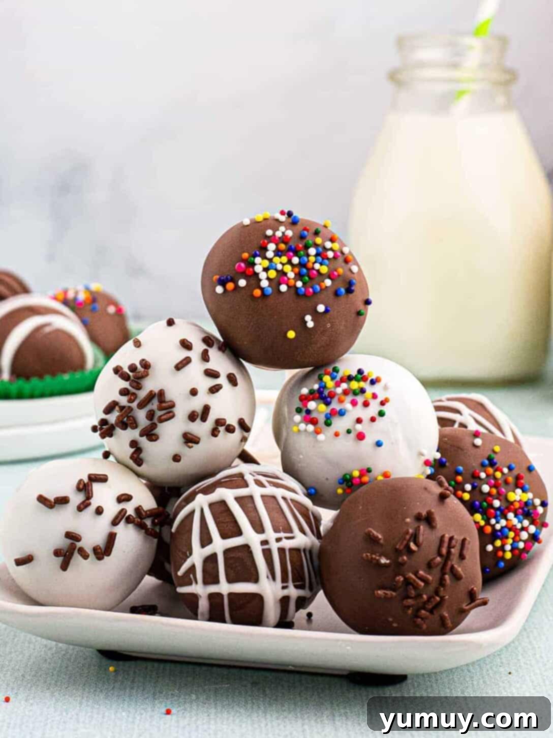 Bite Sized Chocolate Delights 2 Stacked chocolate cake pops on a white plate, showcasing their smooth chocolate coating and festive appearance.