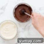 Bite Sized Chocolate Delights 13 Dipping a cake pop into melted chocolate.