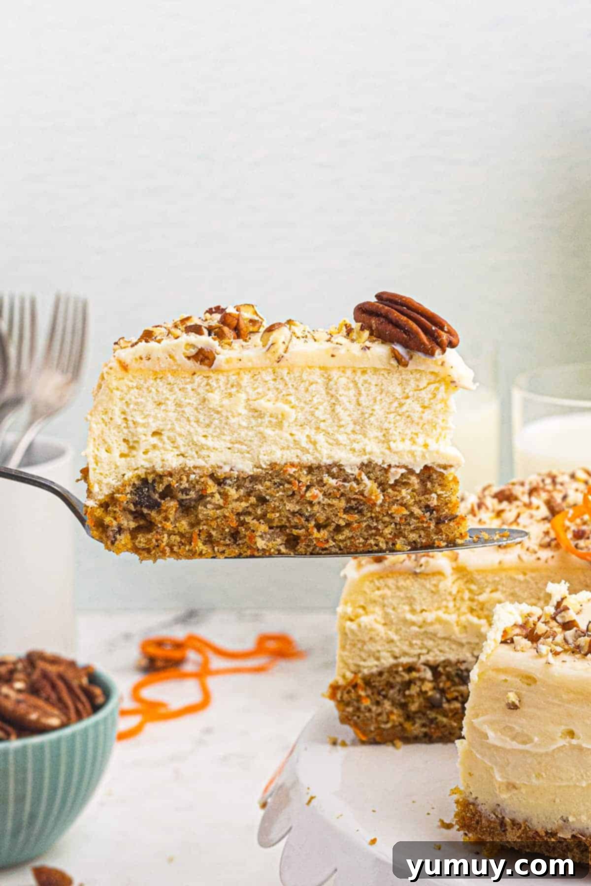 A delectable slice of carrot cake cheesecake being lifted, showcasing its distinct layers of moist carrot cake, creamy cheesecake, and tangy cream cheese frosting.