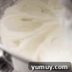 Light and fluffy whipped cream cheese frosting in a stand mixer bowl, ready to be spread.