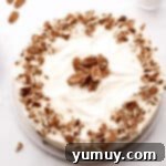 A glorious carrot cake cheesecake, generously topped with creamy cream cheese frosting and sprinkled with chopped nuts.