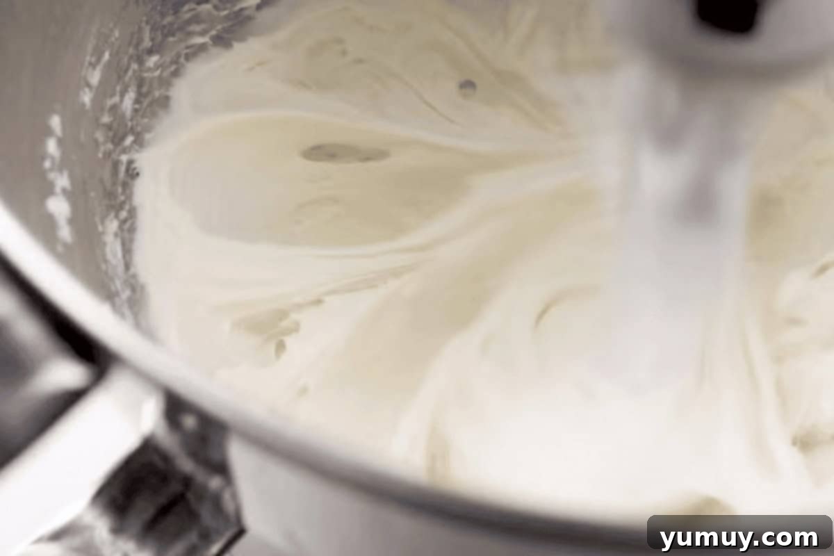 Light and fluffy whipped cream cheese frosting in a stand mixer bowl, ready to be spread.