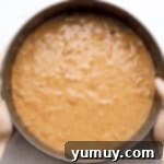 Carrot cake batter carefully poured into a springform pan, forming the base layer.