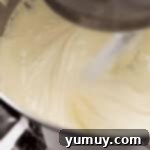 Beating cheesecake batter ingredients in a stand mixer bowl, ensuring a smooth and creamy consistency.