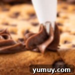 The Legendary Chocolate Chip Cookie Cake 14 piping chocolate frosting onto cookie cake