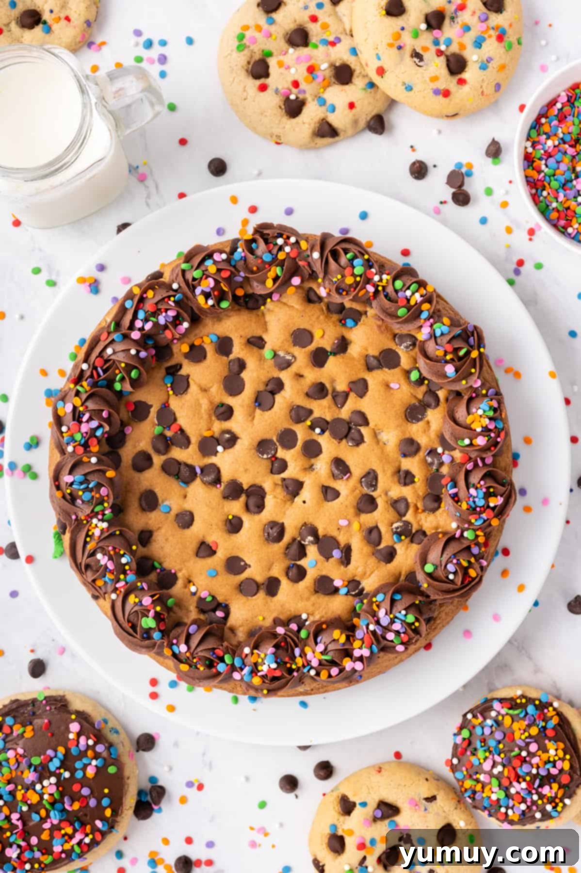 The Legendary Chocolate Chip Cookie Cake 3 chocolate chip cookie cake with frosting and sprinkles on a white serving plate