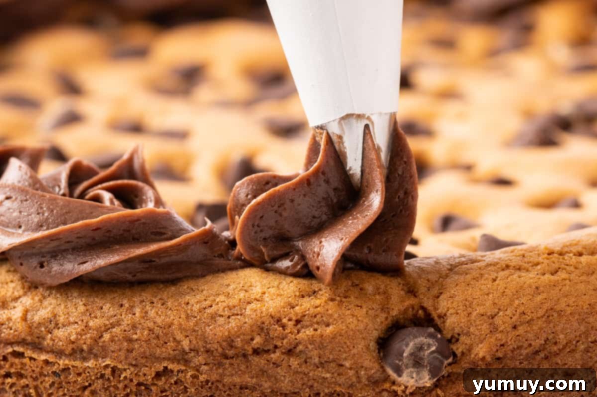 The Legendary Chocolate Chip Cookie Cake 24 piping chocolate frosting onto cookie cake