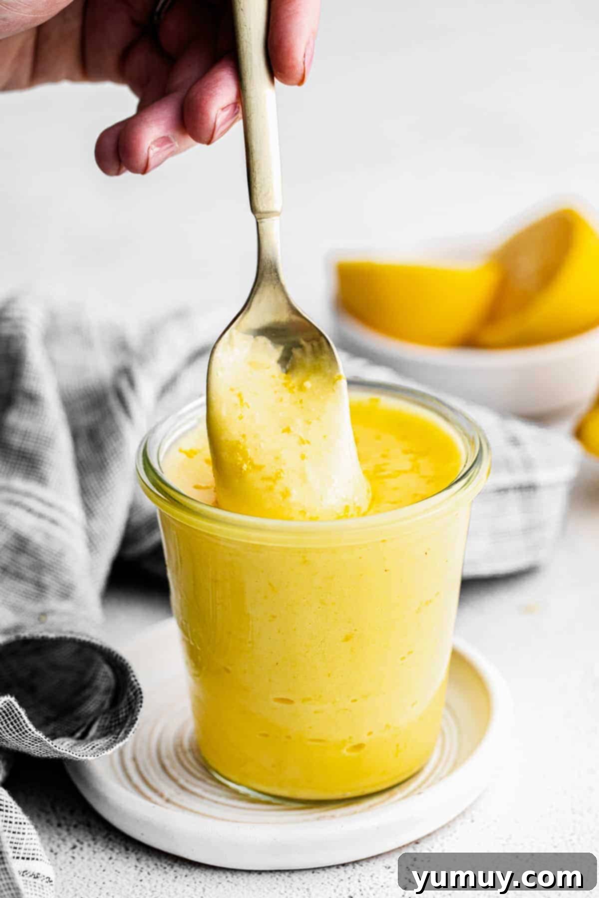 Homemade Lemon Curd: Bright, Tangy Perfection 2 A spoon lifting up rich, creamy, and perfectly tangy homemade lemon curd from a bowl.