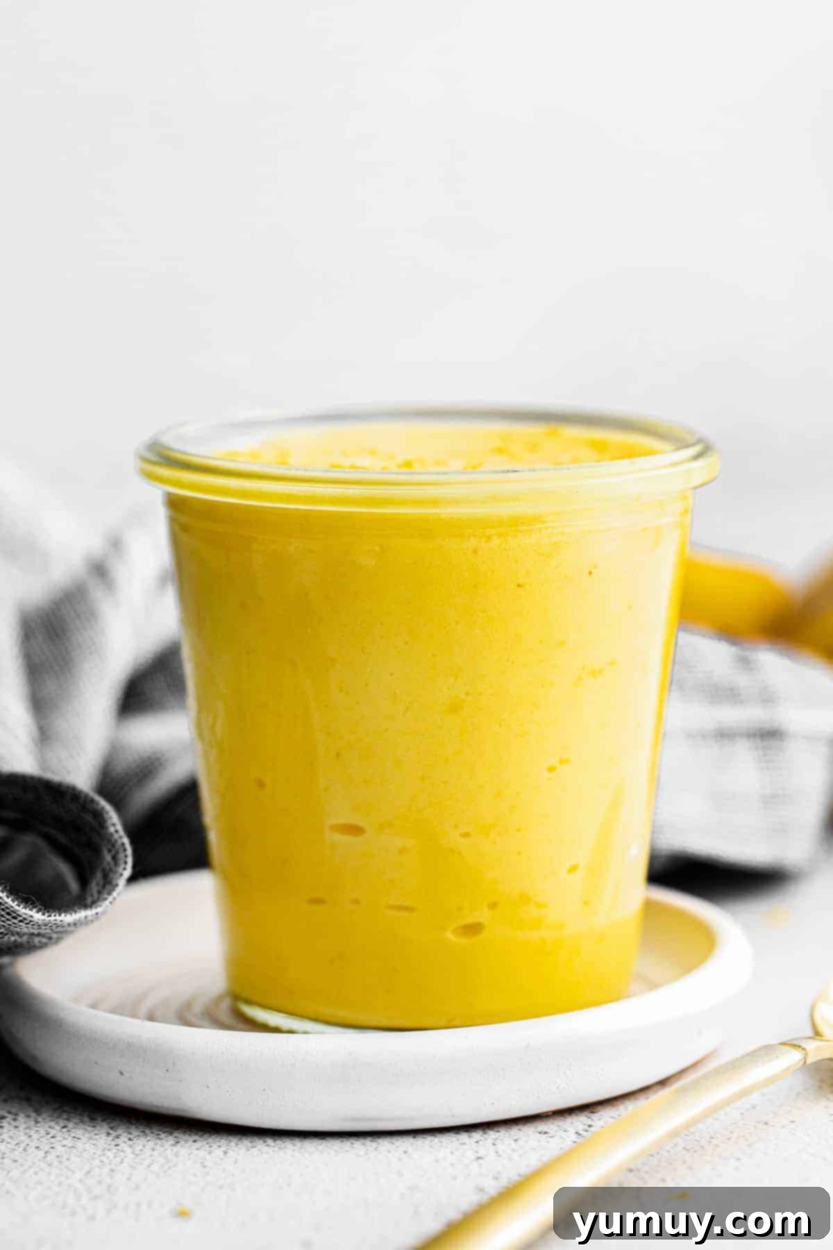 Homemade Lemon Curd: Bright, Tangy Perfection 3 Up close view of creamy lemon curd in a clear glass jar, ready for use.