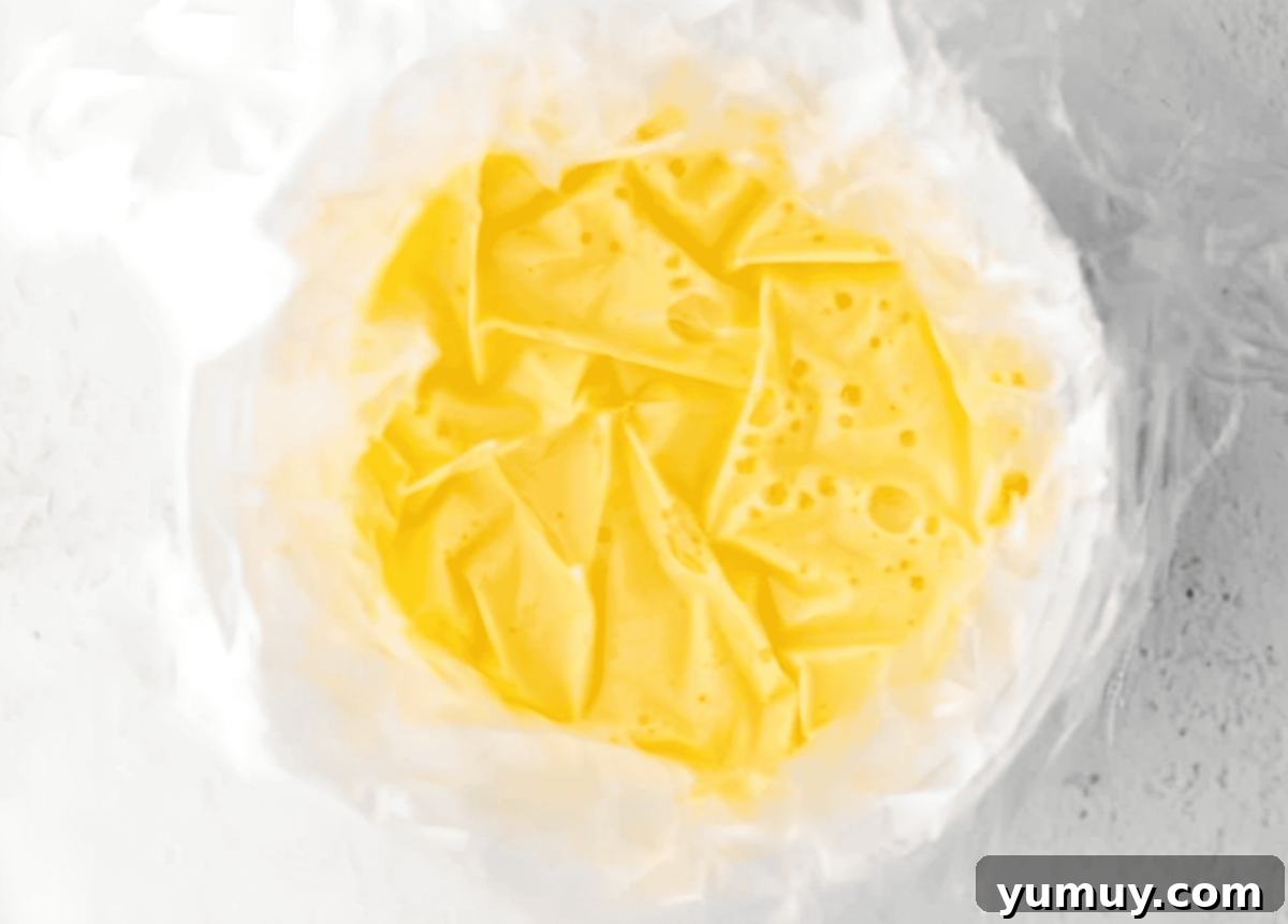 Homemade Lemon Curd: Bright, Tangy Perfection 10 Plastic wrap pressed down onto the surface of the warm lemon curd in a bowl.