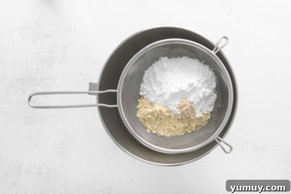 Berry Bliss Macarons 16 sifting flour and almond flour into a bowl with whipped egg whites.