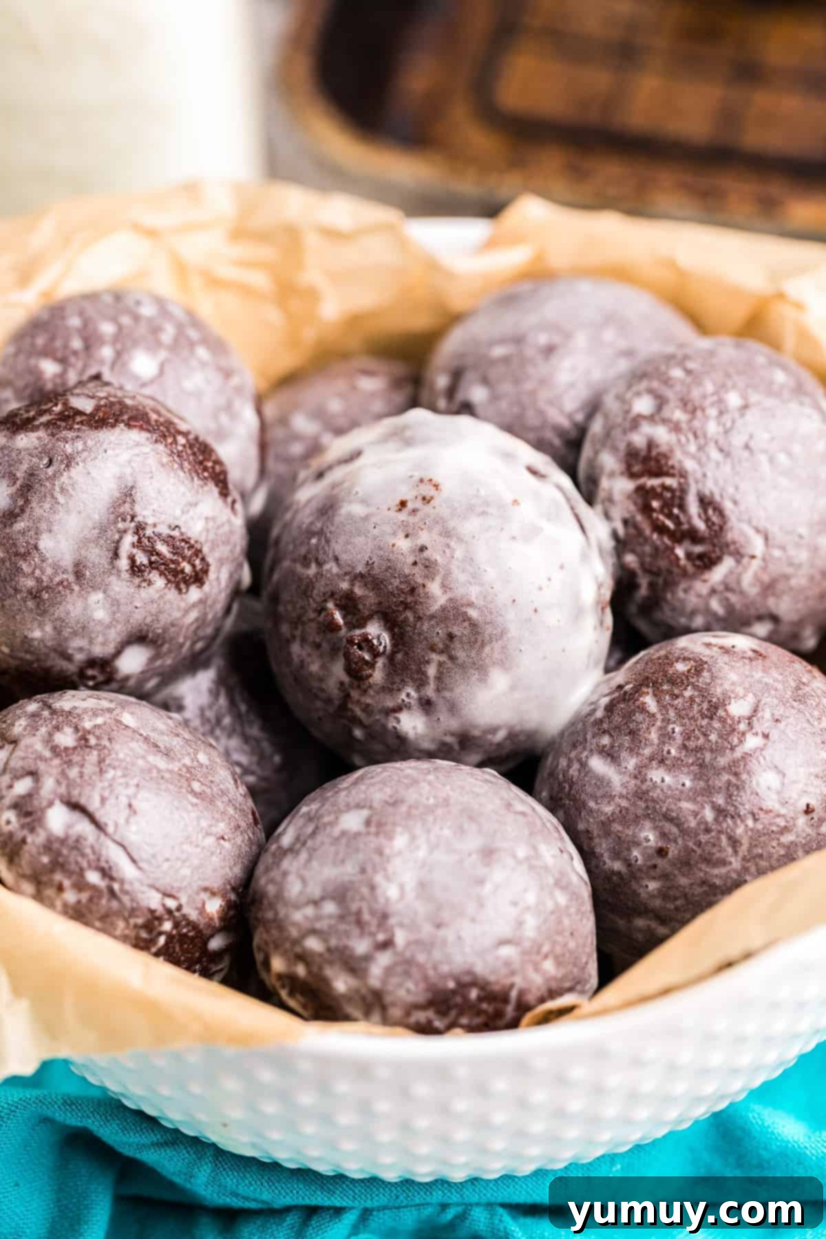 Glazed chocolate donut holes made in an air fryer in a white bowl, ready to be enjoyed.