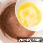 Pouring melted butter into a dry ingredient mixture.