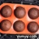 Chocolate donut holes in a silicone mold, in the basket of an Air Fryer.