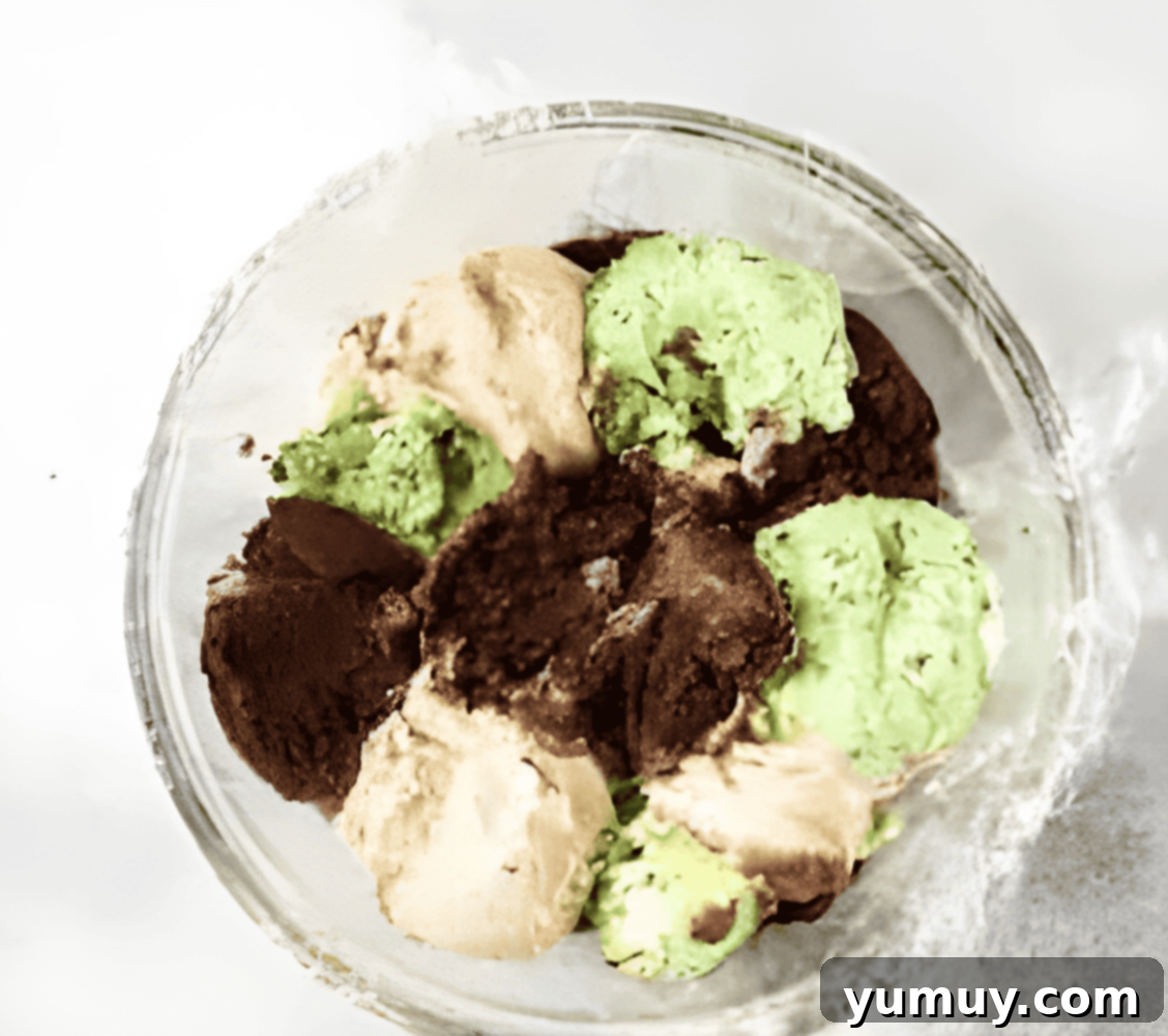 scoops of chocolate, vanilla, and mint chocolate chip ice cream in a plastic wrap-lined glass bowl.