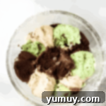 scoops of chocolate, vanilla, and mint chocolate chip ice cream in a plastic wrap-lined glass bowl.
