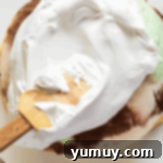 spreading meringue over an ice cream dome on a white plate.