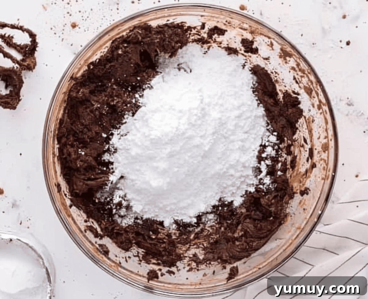 Velvet Chocolate Buttercream 11 powdered sugar over beaten chocolate butter in a glass bowl.
