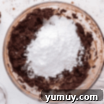 Velvet Chocolate Buttercream 6 powdered sugar over beaten chocolate butter in a glass bowl.