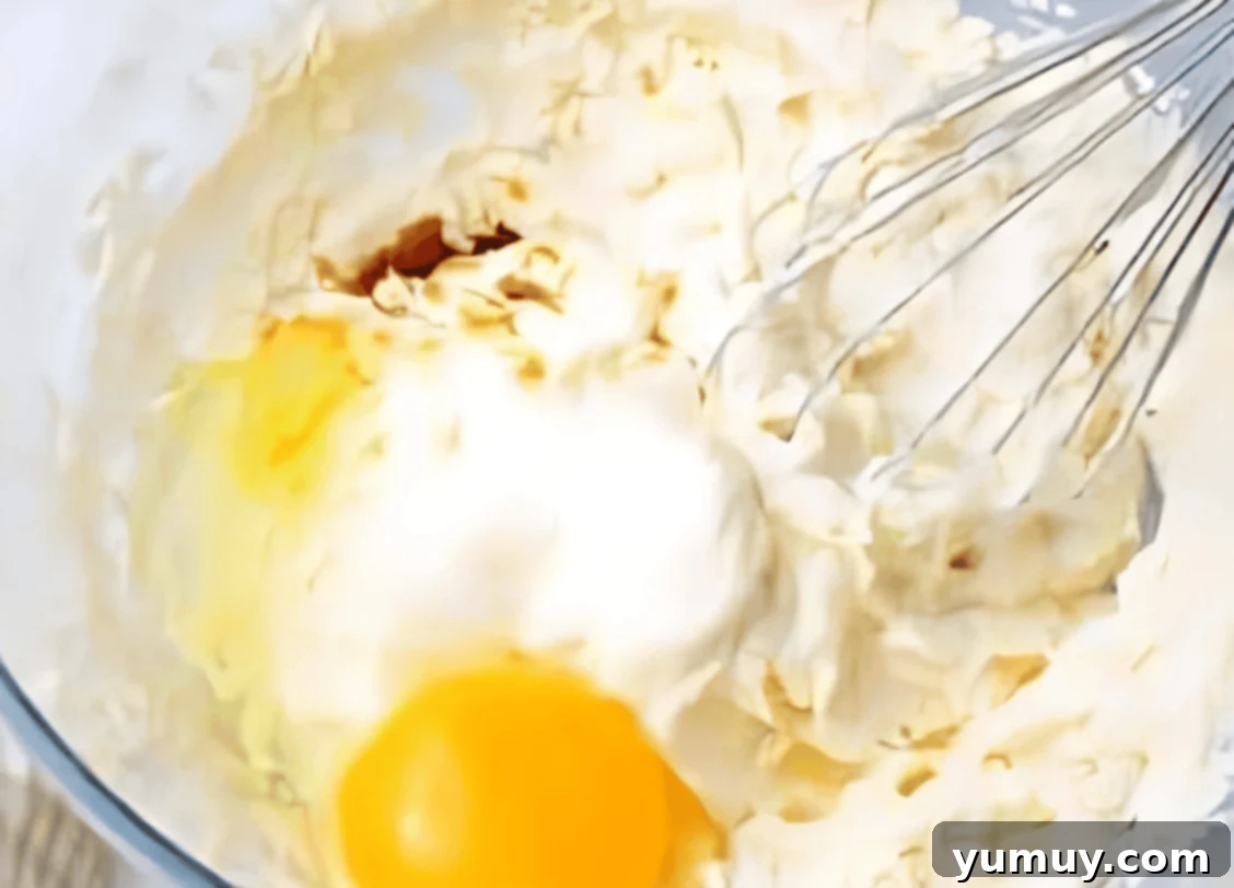 adding eggs to batter in a bowl with a whisk.