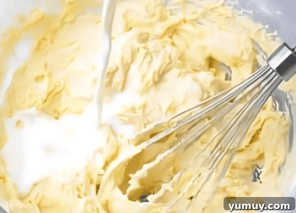 adding buttermilk to batter in a bowl with a whisk.