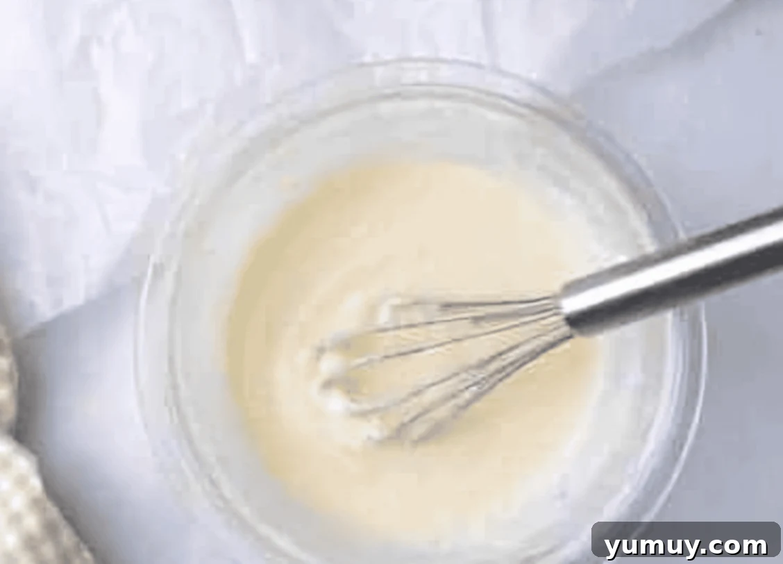 white glaze in a glass bowl with a whisk.