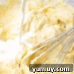 adding buttermilk to batter in a bowl with a whisk.