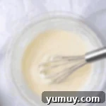 white glaze in a glass bowl with a whisk.