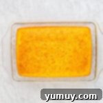 The baked yellow cake in a glass baking dish, with numerous holes already poked into its surface, ready to absorb the pastry cream.