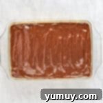 The completed Boston Cream Pie Poke Cake, topped with glistening chocolate ganache in a glass baking dish, ready to be sliced.