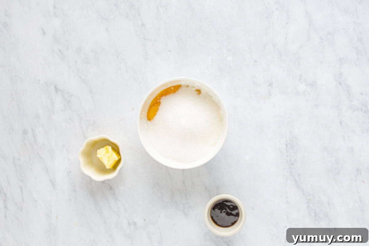 A close-up view of egg yolks, granulated sugar, and cornstarch, expertly whisked together into a smooth, pale yellow mixture in a white bowl.