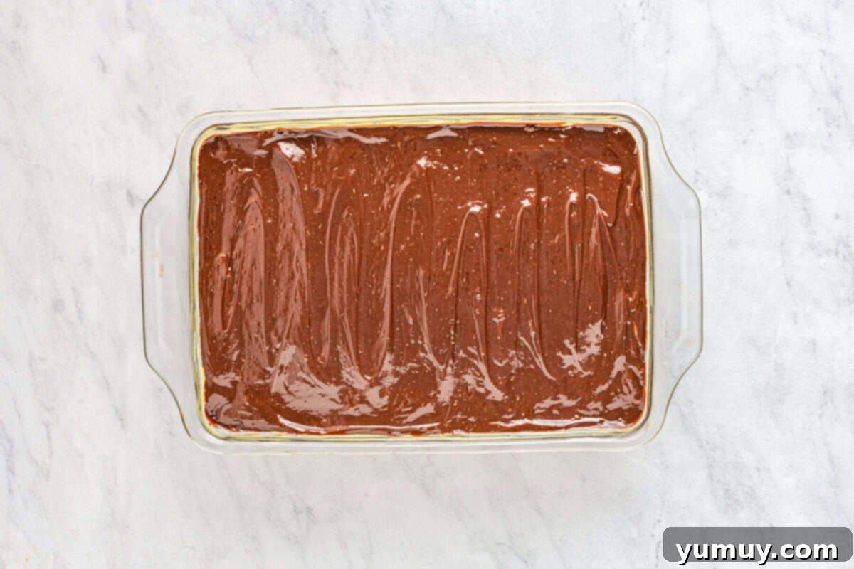 The completed Boston Cream Pie Poke Cake, beautifully topped with glistening chocolate ganache in a glass baking dish, ready to be sliced and served.