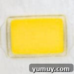 Yellow cake batter filling a glass baking dish, smoothly spread and ready for the oven.