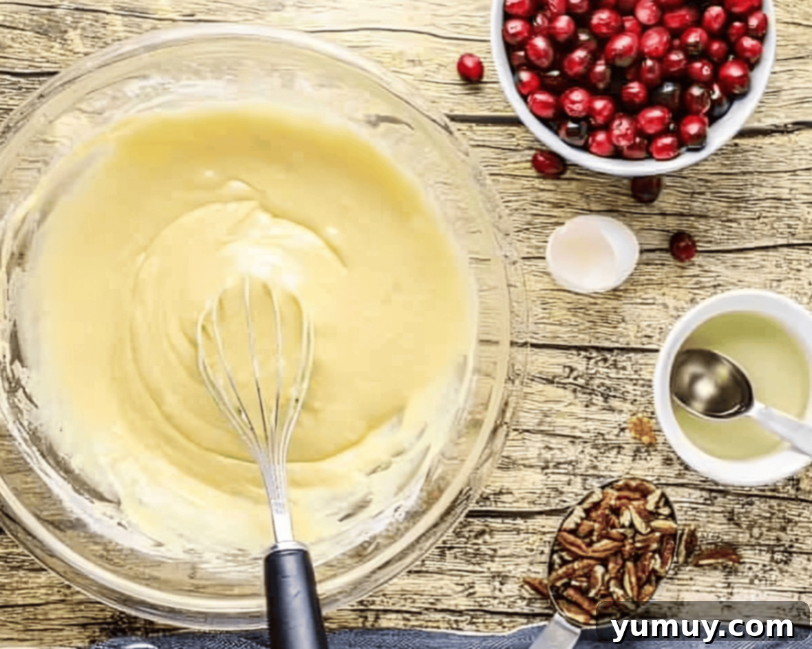 A vibrant yellow muffin batter being gently whisked in a clear glass bowl, showcasing its smooth yet slightly lumpy consistency, indicative of proper mixing.