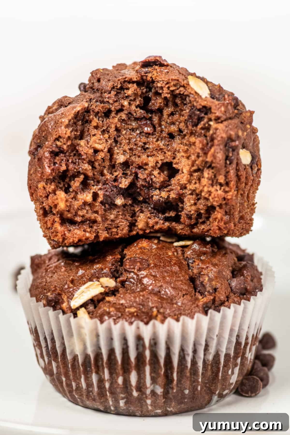 Chocolate Oatmeal Bliss Muffins 3 Two perfectly stacked healthy chocolate oatmeal muffins on a white surface