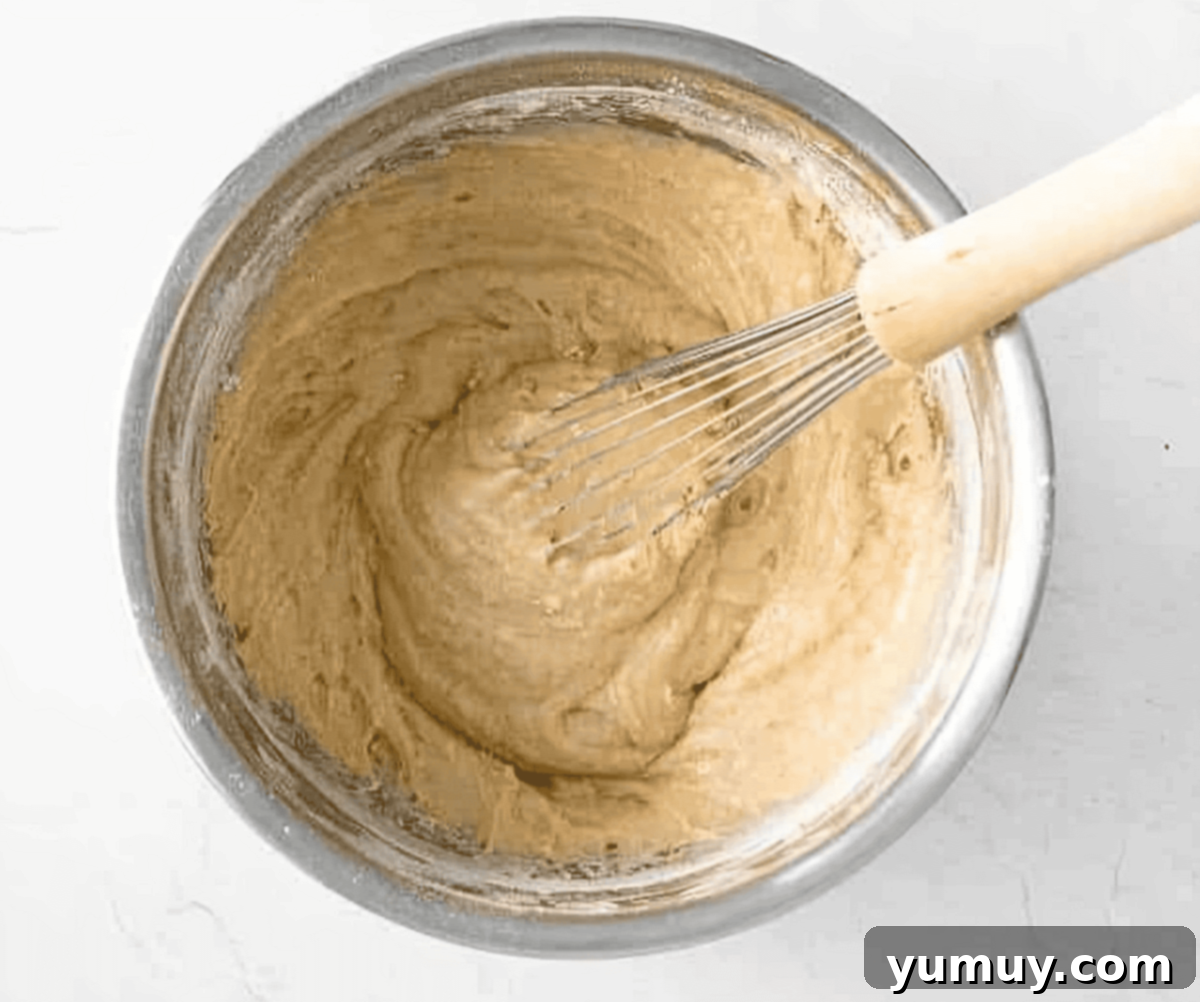 muffin batter in a stainless mixing bowl with a whisk.