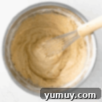 muffin batter in a stainless mixing bowl with a whisk.