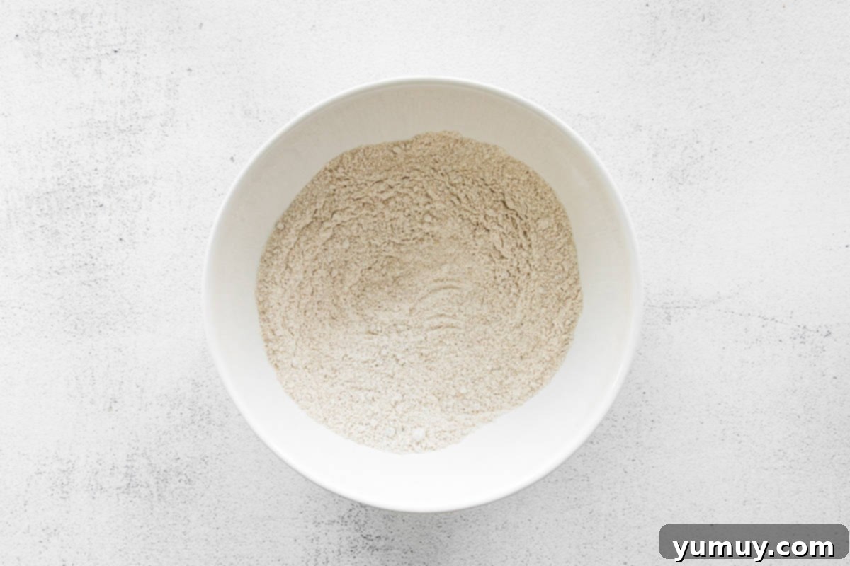 A white bowl holding vanilla cake mix and chai spice, ready to be whisked together.