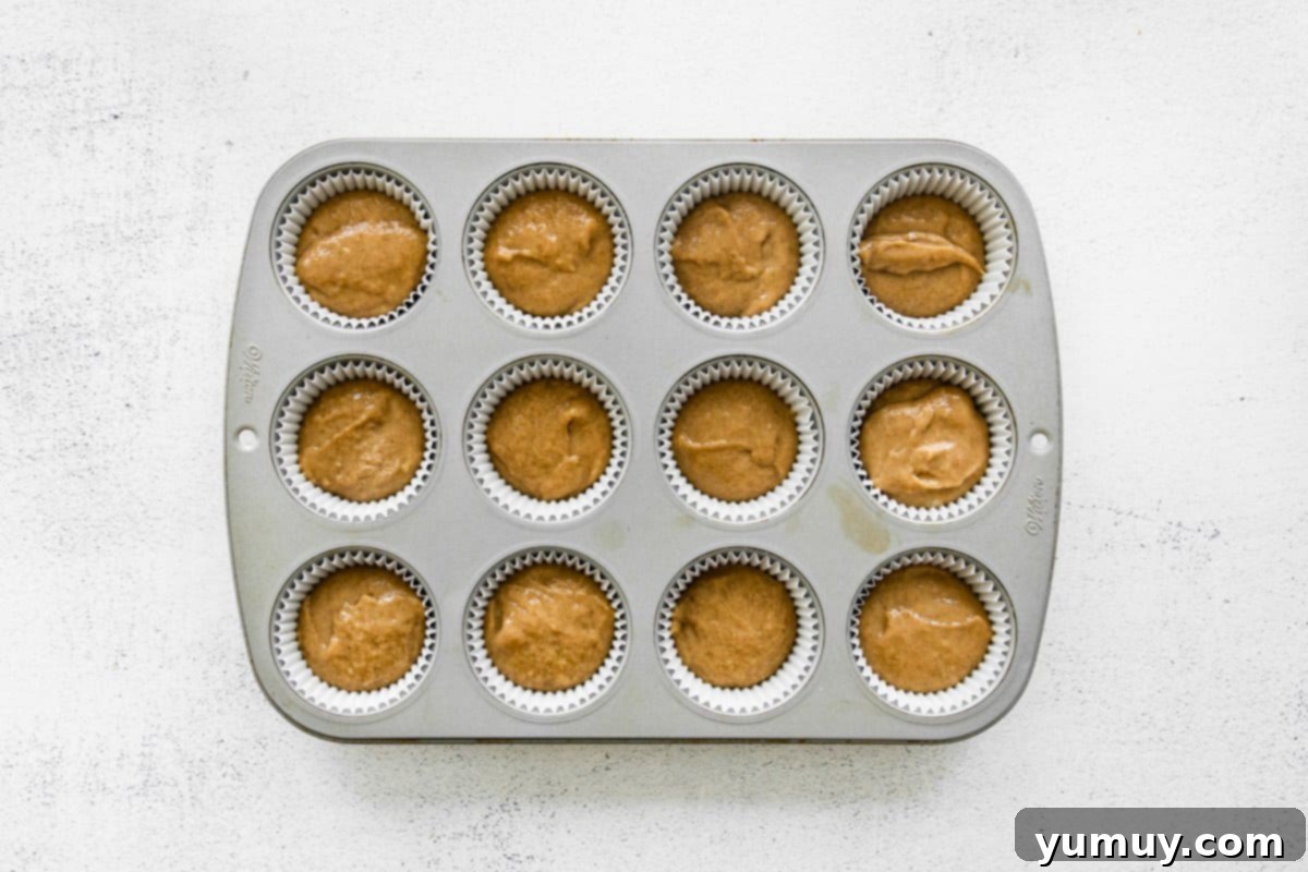 Chai tea cupcake batter meticulously portioned into a cupcake tin, prepared for oven baking.