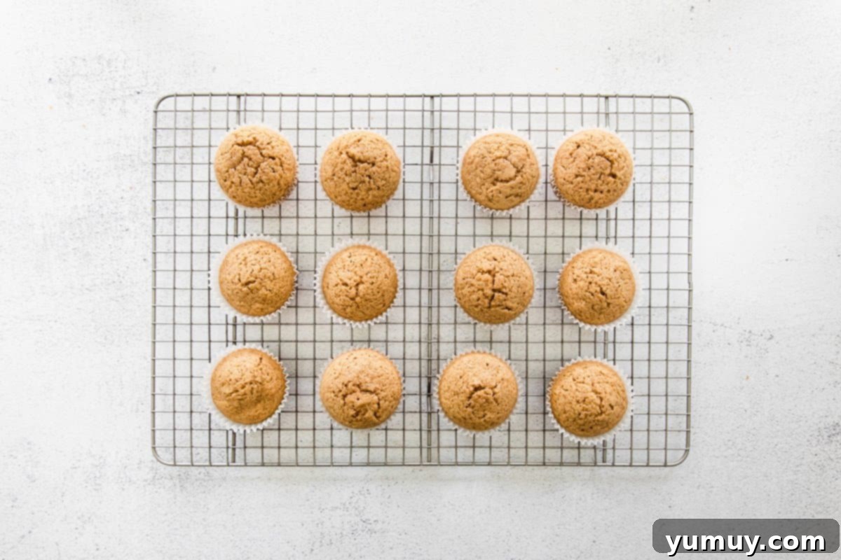 A baker's dozen of baked chai cupcakes arranged neatly on a wire rack, cooling down.